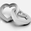 Two silver metal lovehearts intertwined seamlessly