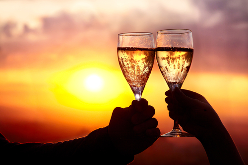 Celebrate A Wedding Anniversary On A Budget. A couple toasting at sunset.