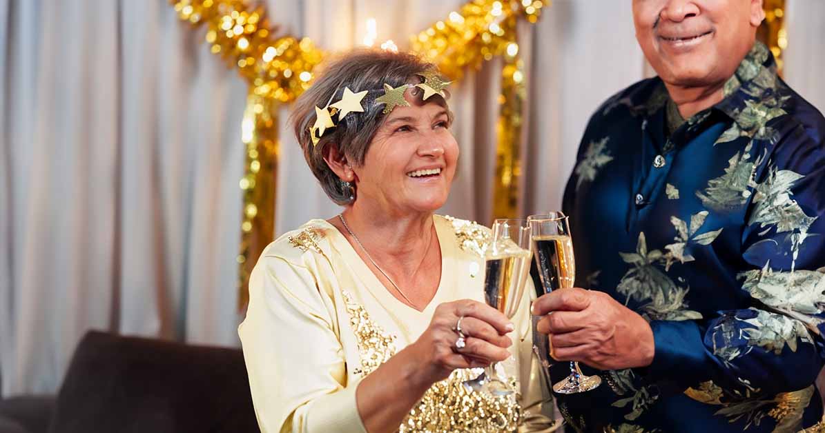 Golden wedding Celebration with wife wearing golden garland, clinking champagne glasses with her husband of 50 years